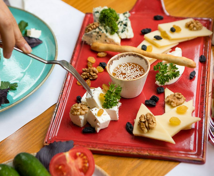 Tabla de quesos variados con frutos secos, frutas y miel