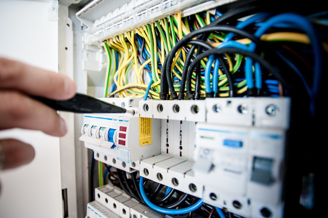 Electricista trabajando en un cuadro eléctrico abierto con cableado de colores y automáticos