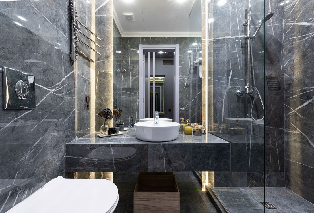 Baño moderno con lavabo blanco y ducha de cristal en tonos neutros