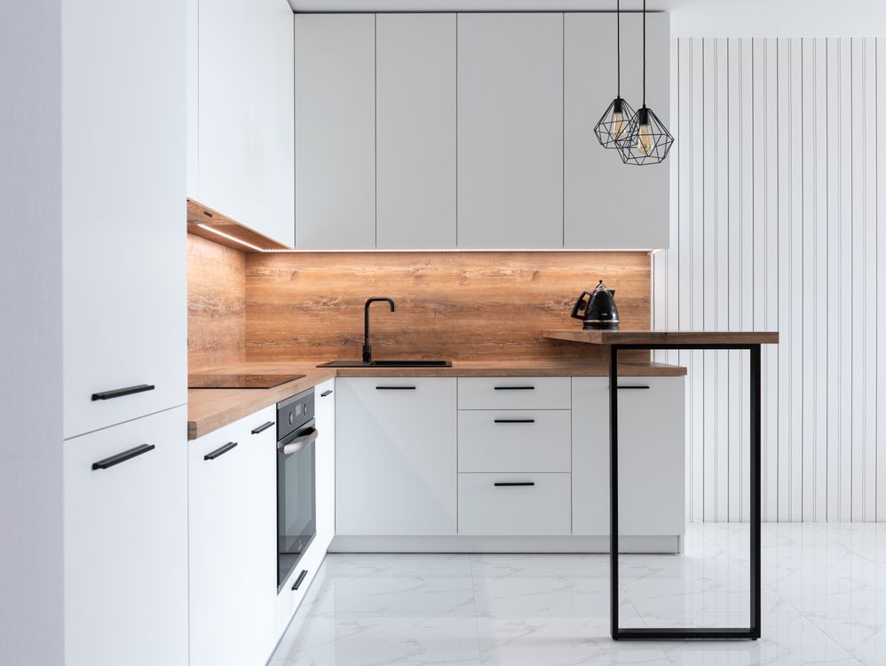 Cocina moderna reformada con muebles blancos y encimera de madera clara