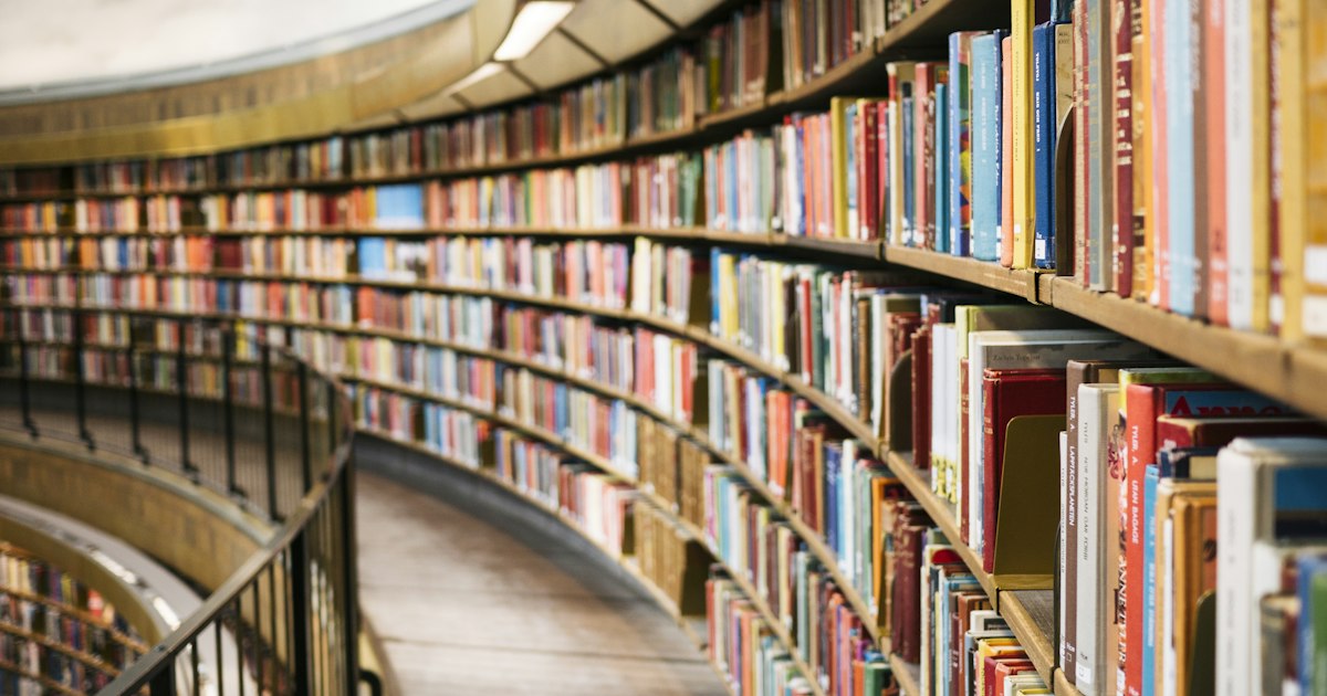 Libros antiguos encuadernados en piel sobre estanterías de madera