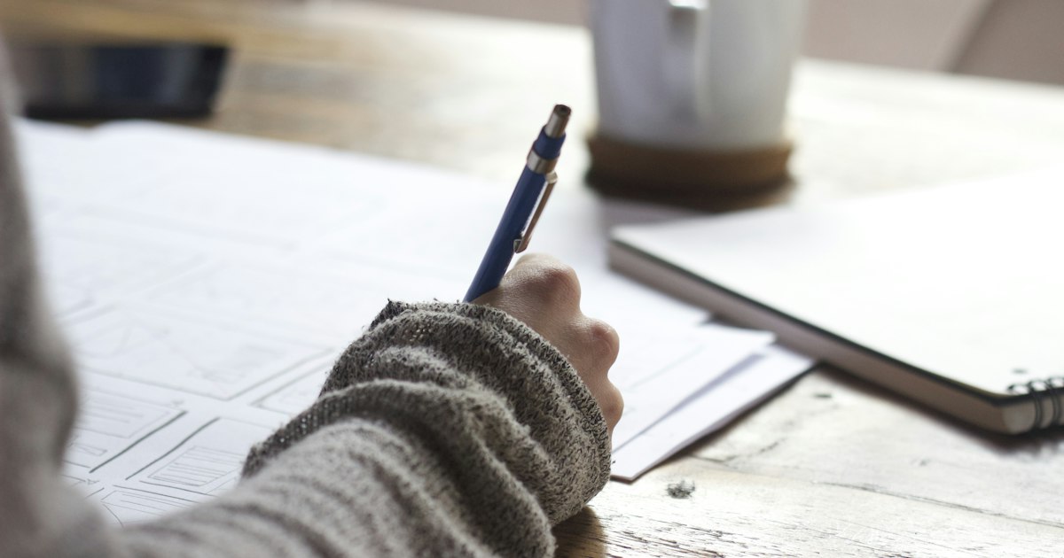 Estudiante concentrado escribiendo notas en un cuaderno mientras planifica sus metas profesionales