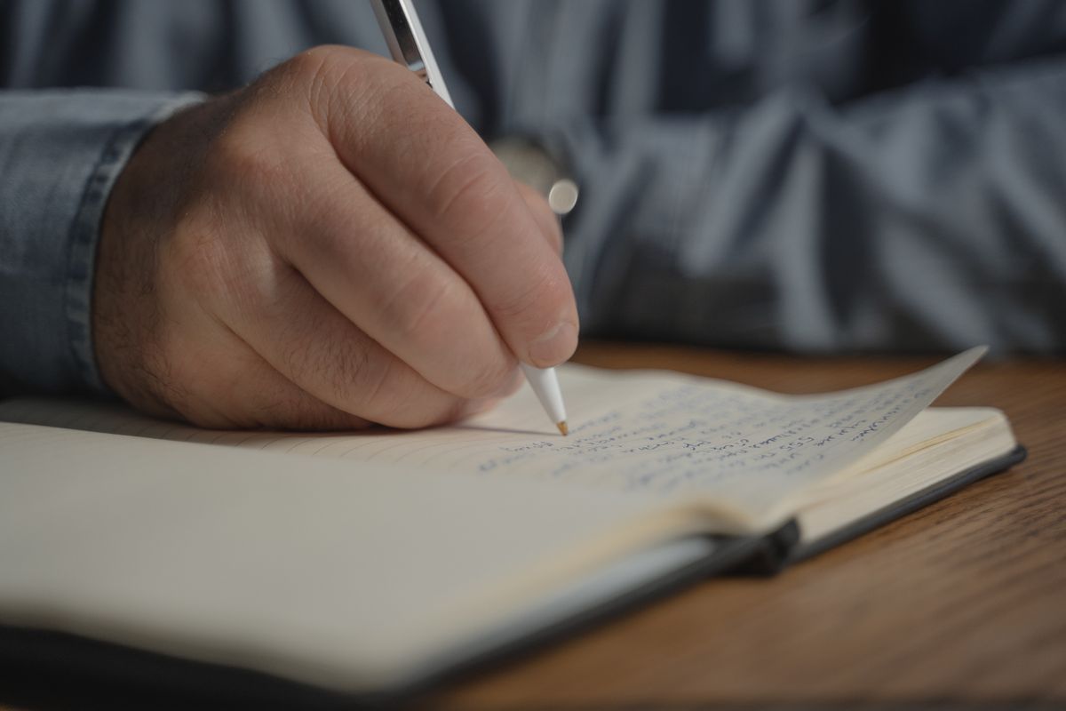 Persona escribiendo reflexiones en un cuaderno de autoconocimiento