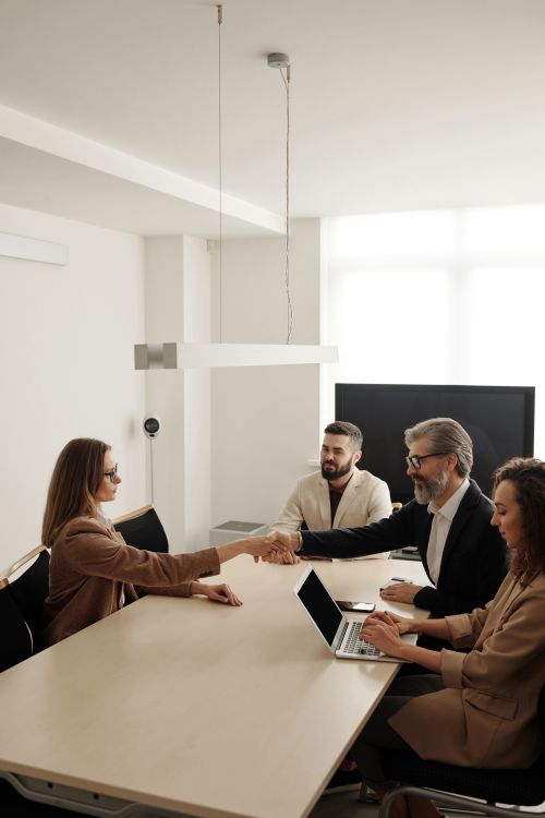 Profesionales de negocios estrechan manos en mesa de conferencias simbolizando colaboración exitosa