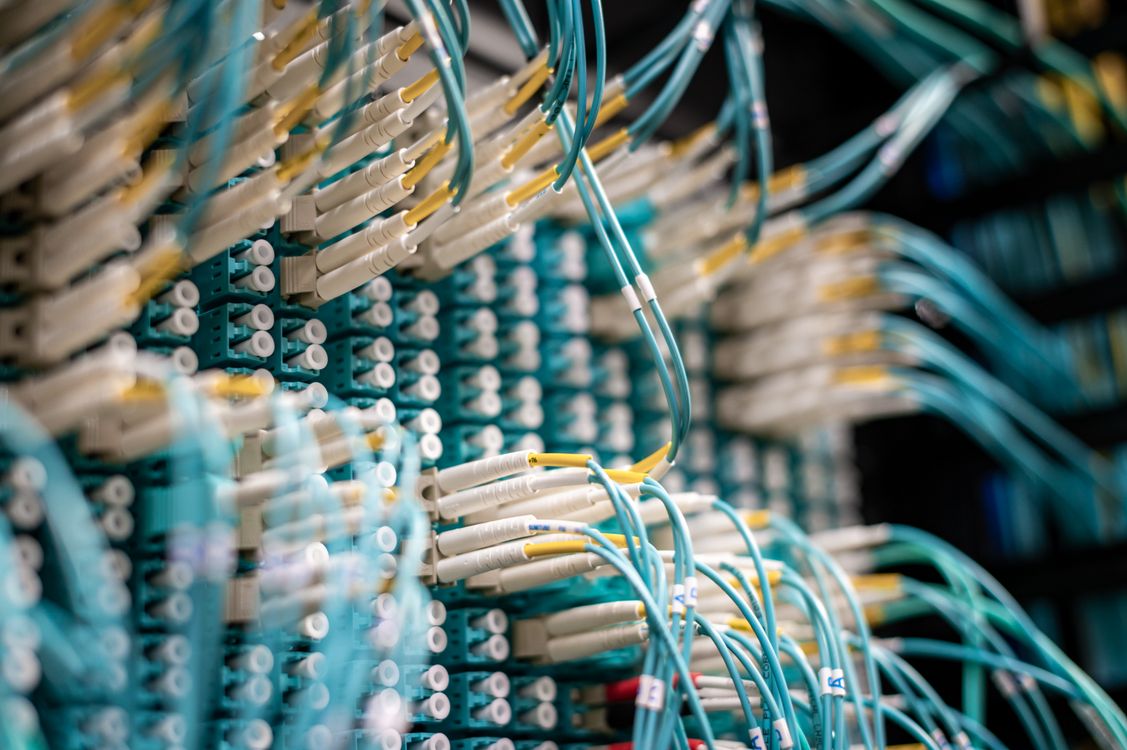 Cables de fibra óptica azules conectados a un switch de red en infraestructura de telecomunicaciones