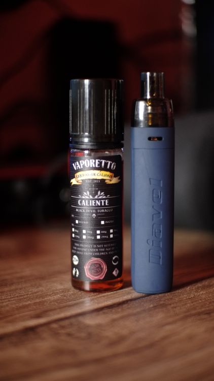 Dispositivo de vapeo recargable con botella de e-líquido sobre una mesa de madera