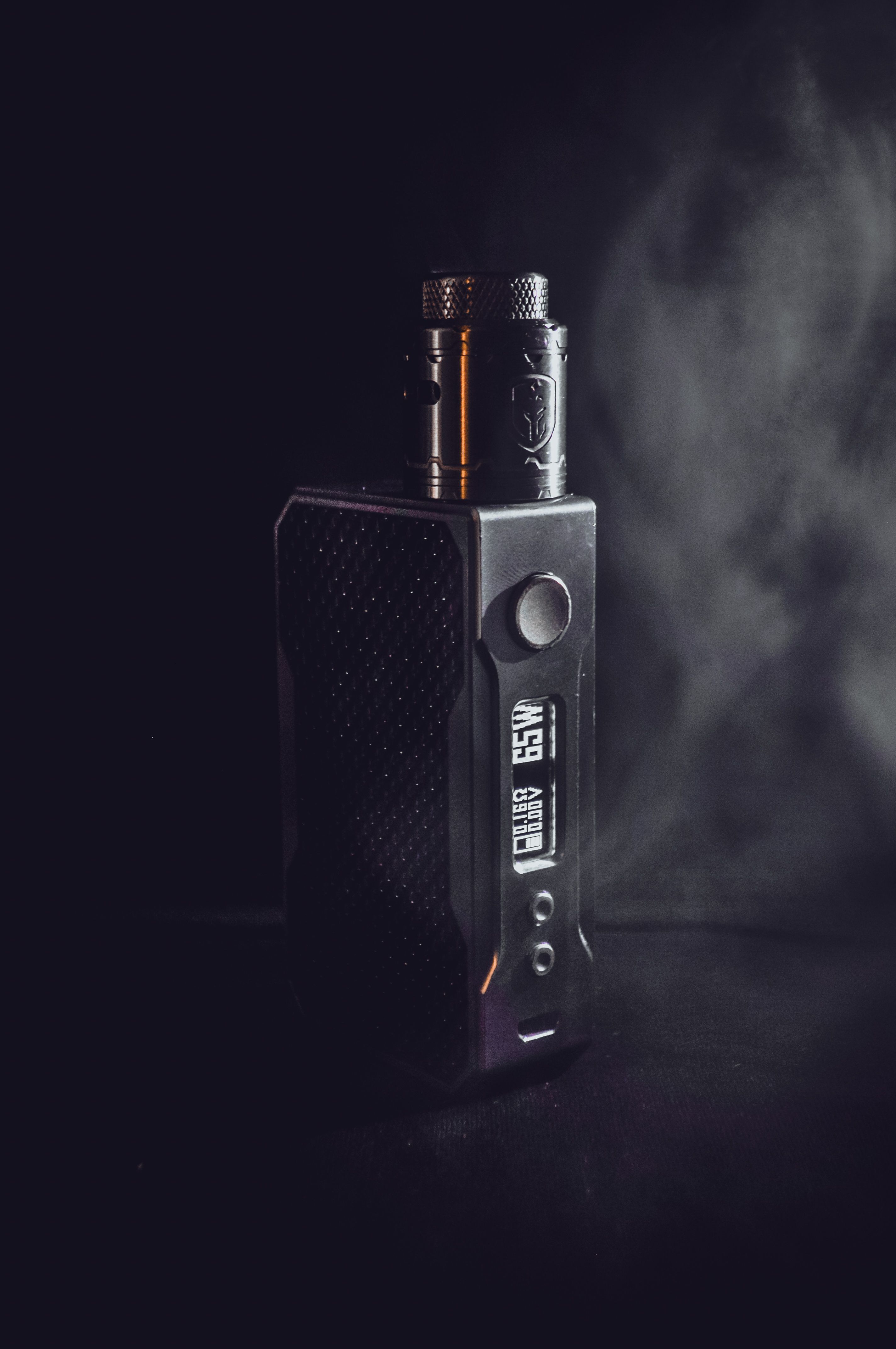 Primer plano de un dispositivo de vapeo con fondo oscuro que resalta acabados y materiales