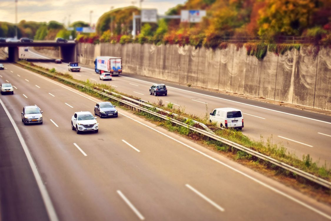 Carros e caminhões trafegando em rodovia brasileira sob céu ensolarado