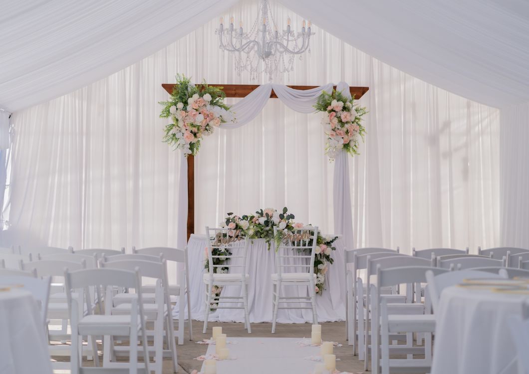 Wedding ceremony space with draped fabric, florals and layered lighting