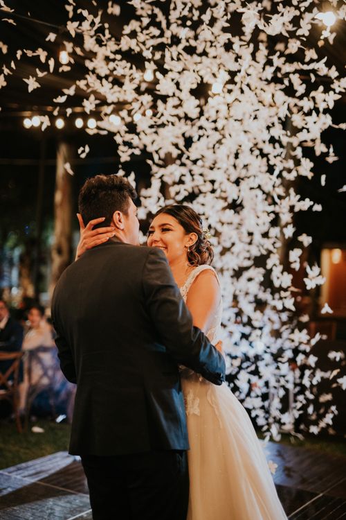 Newlywed couple dancing while showered with petals at their wedding celebration