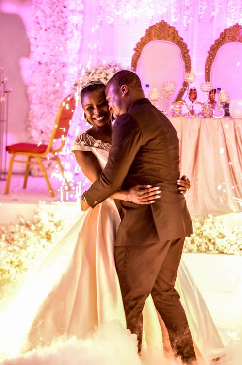 Bride in white gown and groom in black suit sharing their first dance at an elegant wedding reception