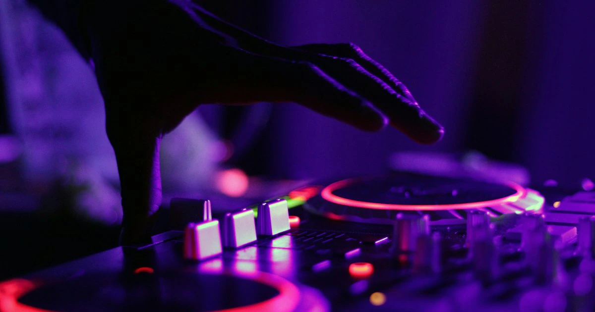Wedding DJ performing at a mixer console with colorful stage lights during a reception