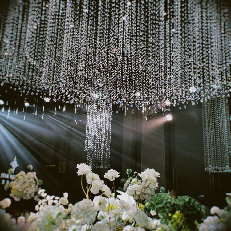 Elegant wedding venue with chandeliers and floral decor creating a warm, illuminated atmosphere