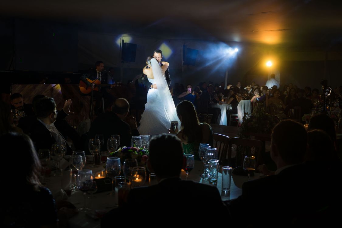 Bride and groom share a romantic first dance under glowing reception lights.