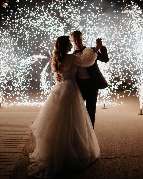 Bride and groom dancing with fireworks lighting up the night sky