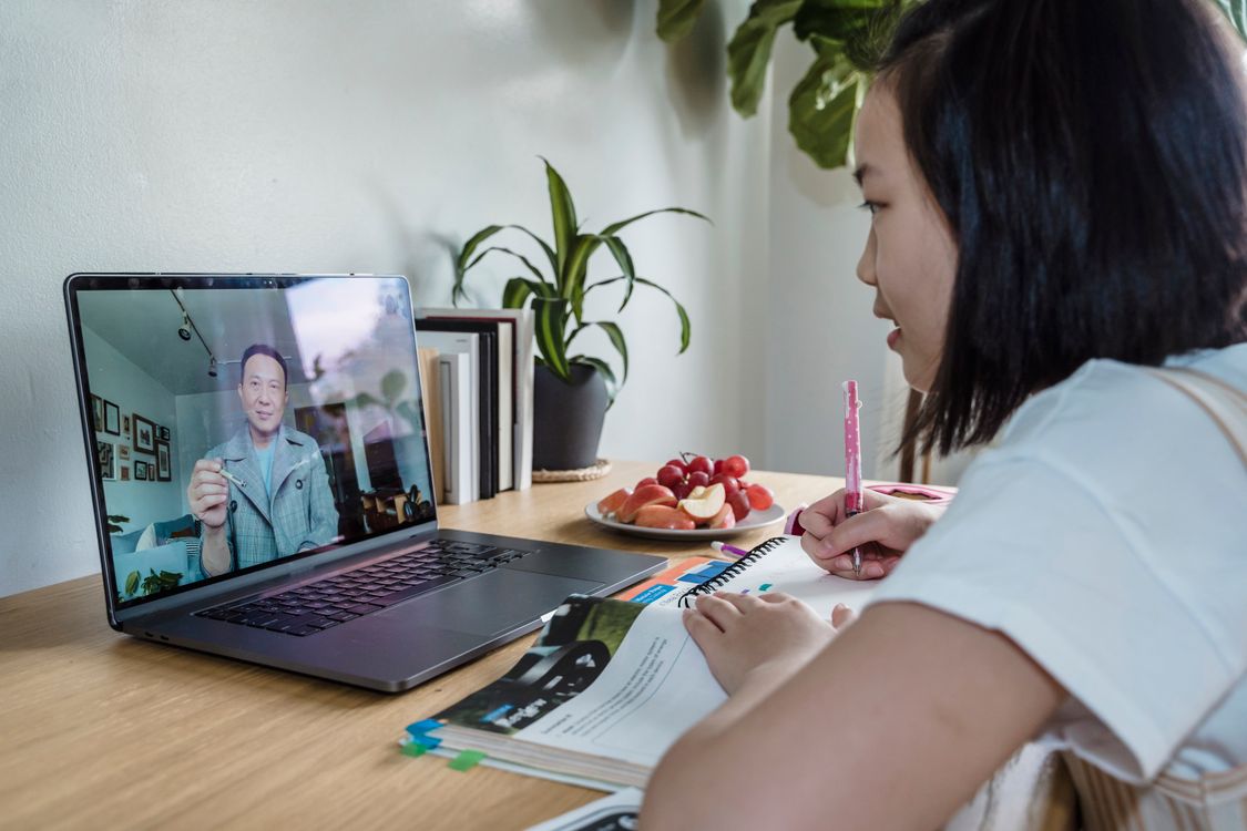Student attending an online class with laptop and notes on a desk