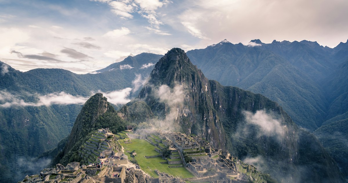 Panoramic view of Machu Picchu ruins and Inca terraces rising against misty Andean peaks in Peru