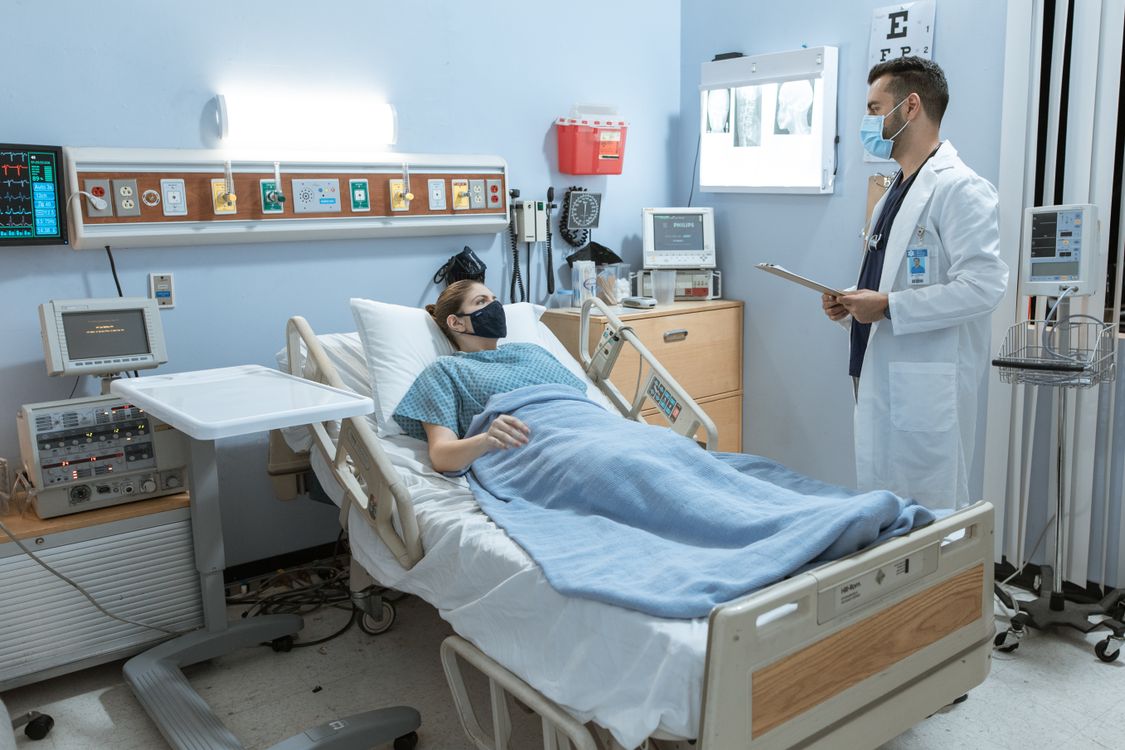 Médico atendiendo a un paciente en una cama de hospital