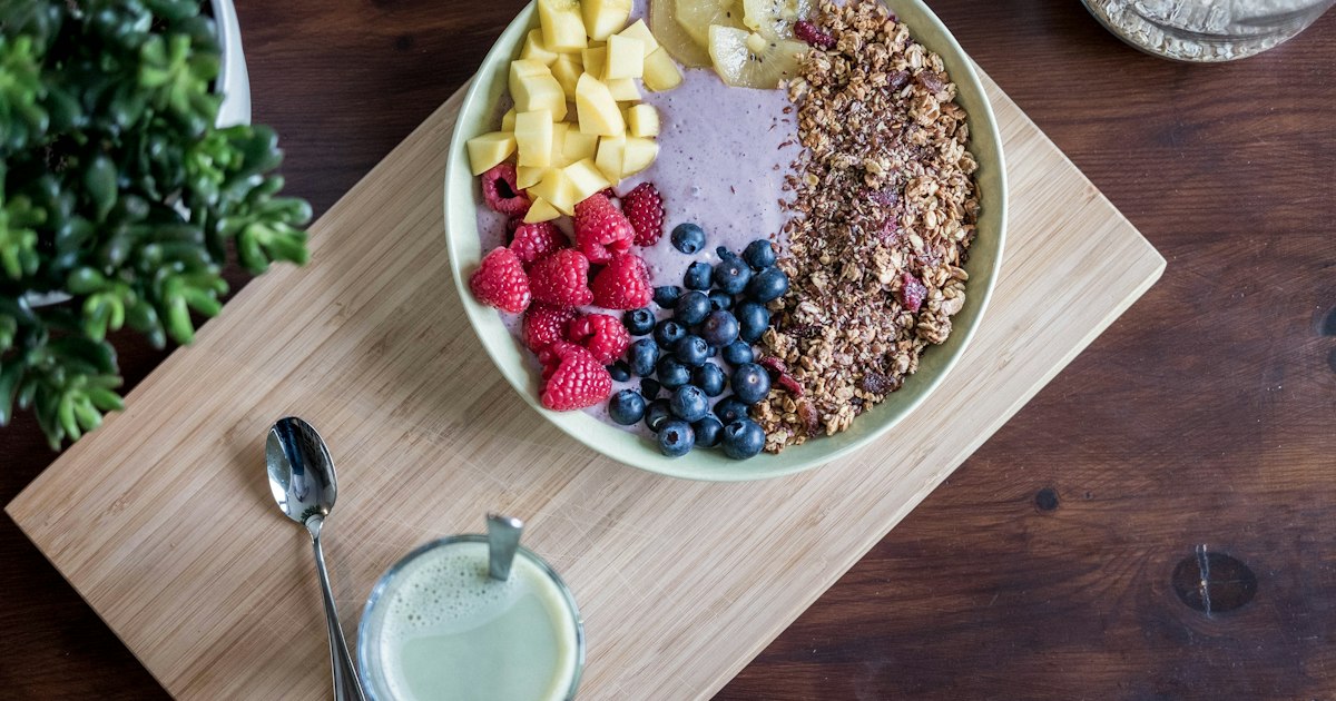 Frutta fresca e frutta secca in ciotole di legno, ingredienti di una colazione paleo senza cereali