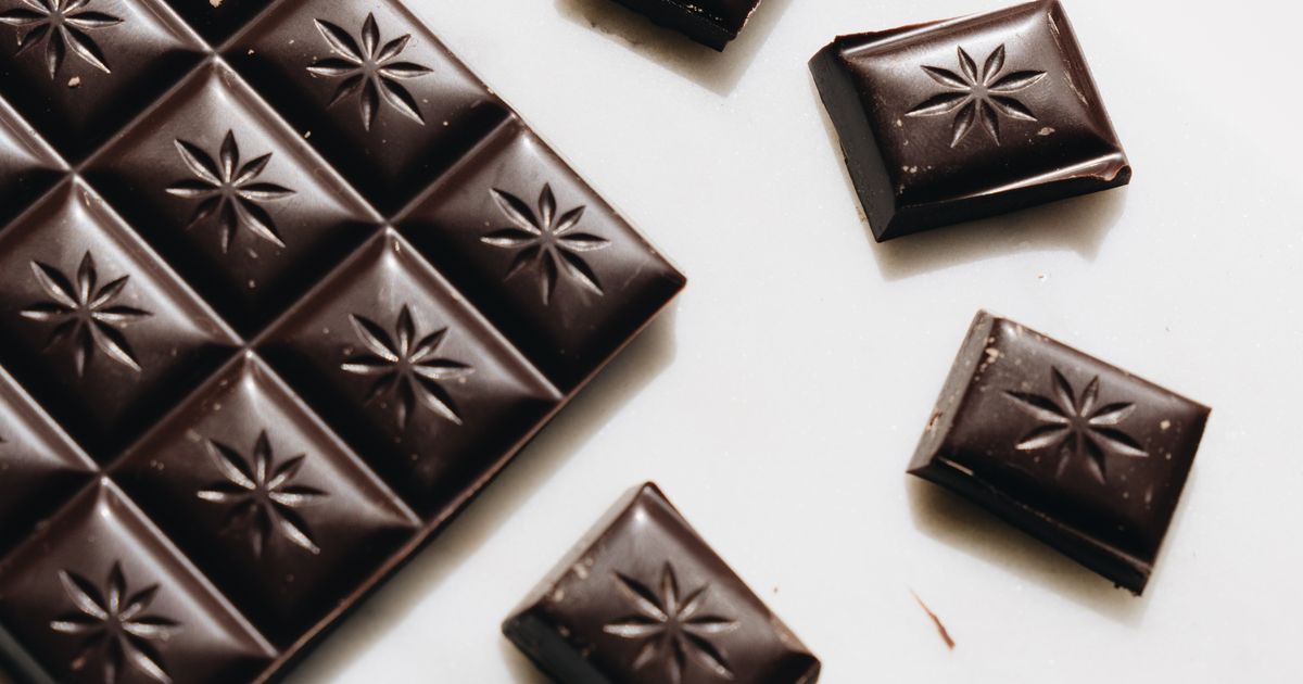 Pezzi di cioccolato fondente su superficie bianca, snack paleo senza zucchero