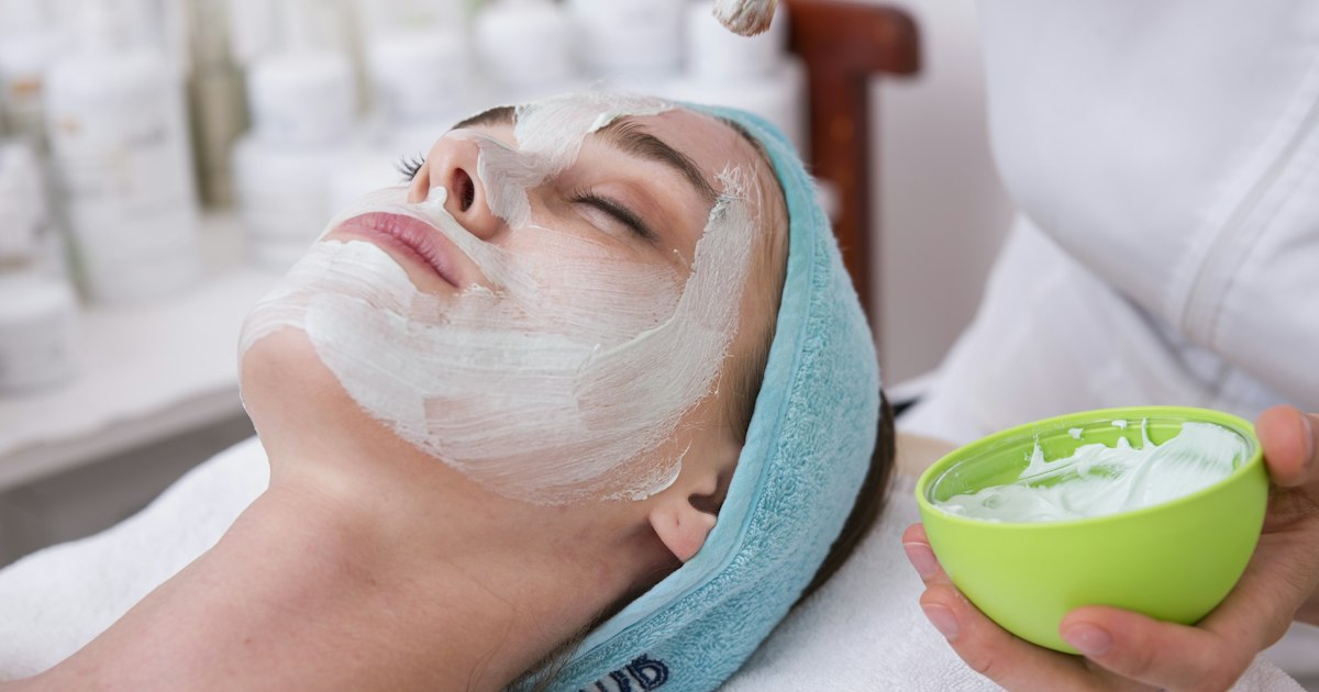 Mujer joven aplicando crema facial para el cuidado de la piel