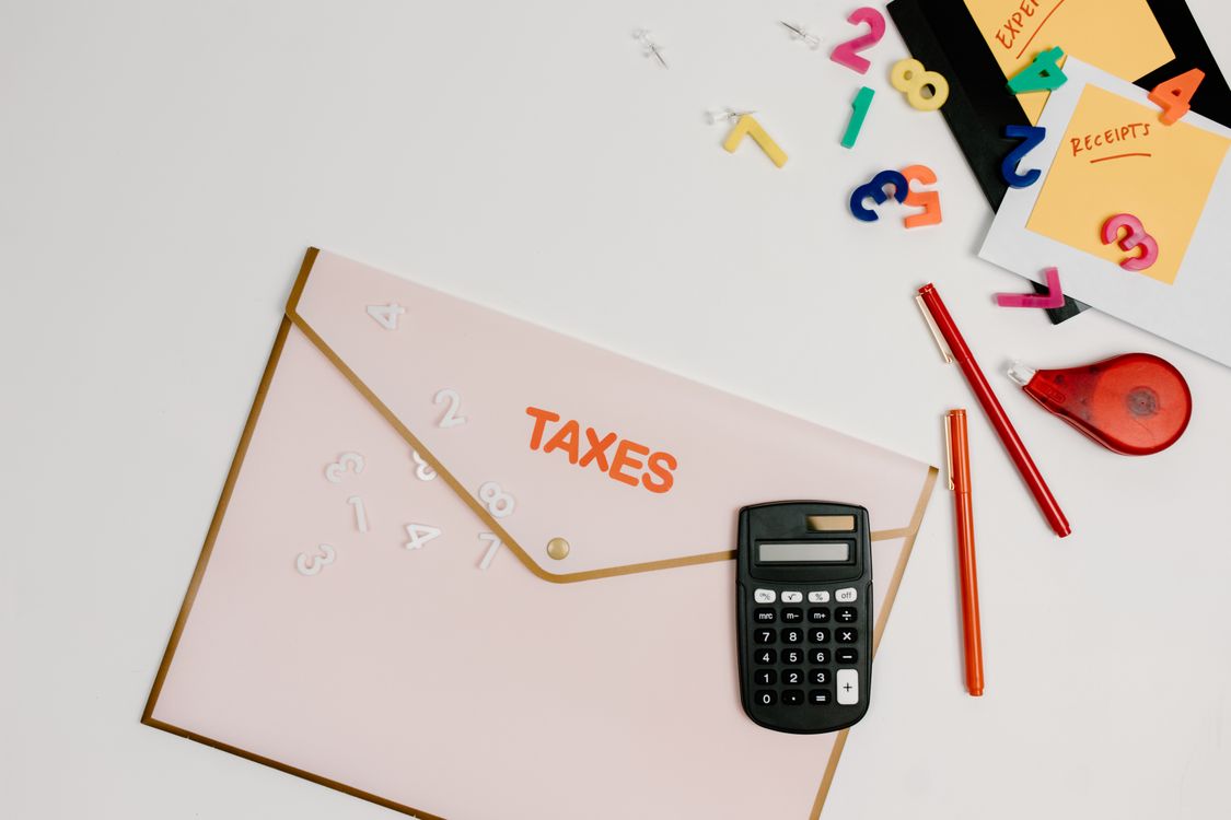 Calculadora sobre papel impresso com números coloridos em preparação tributária