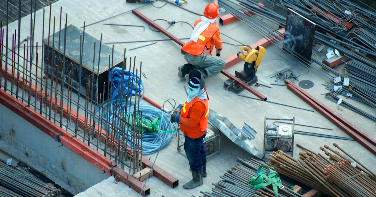 Construction workers in high-visibility vests and hard hats at a building site in the Middle East