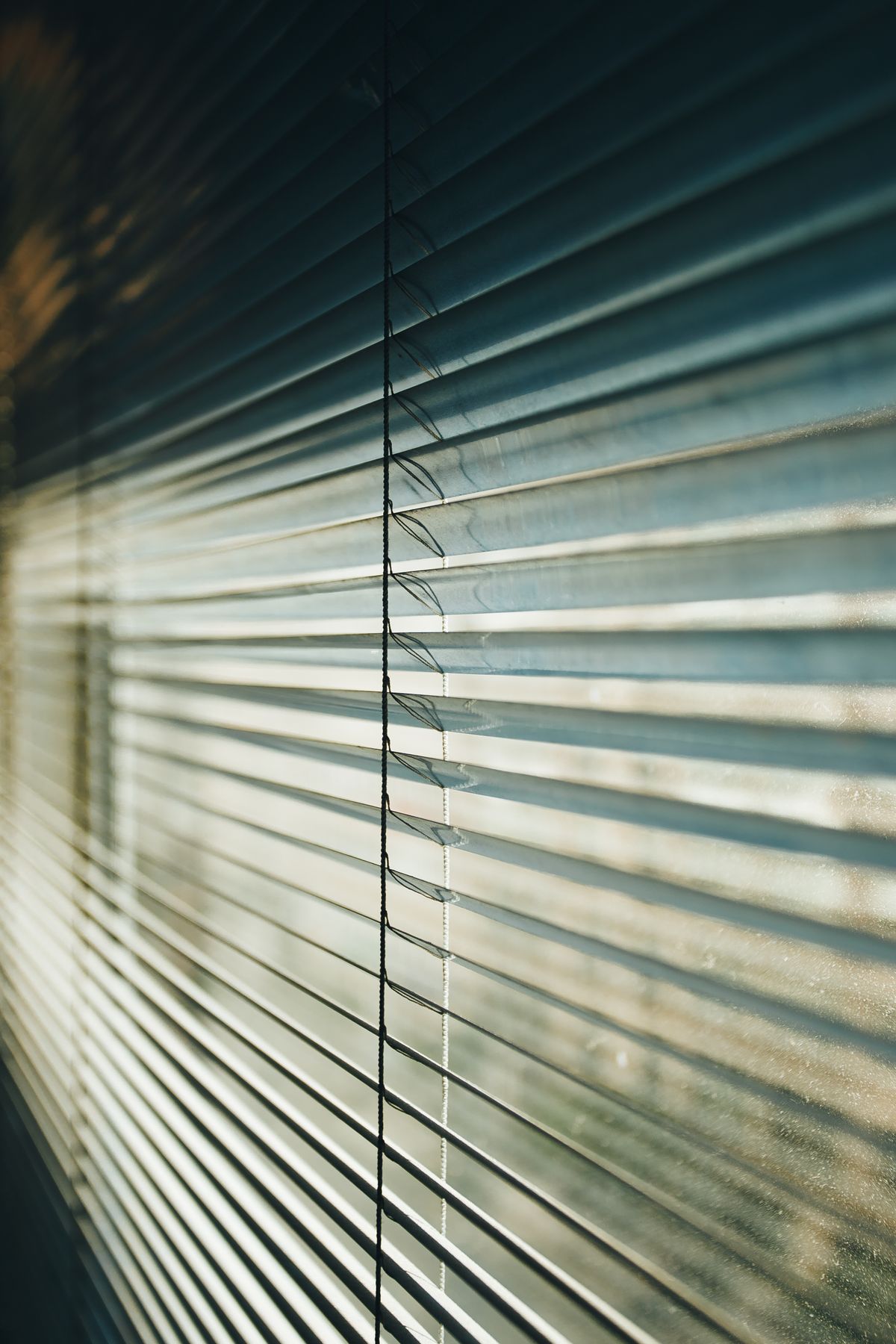 Luz del sol filtrándose a través de las láminas de una cortina clara en un interior moderno