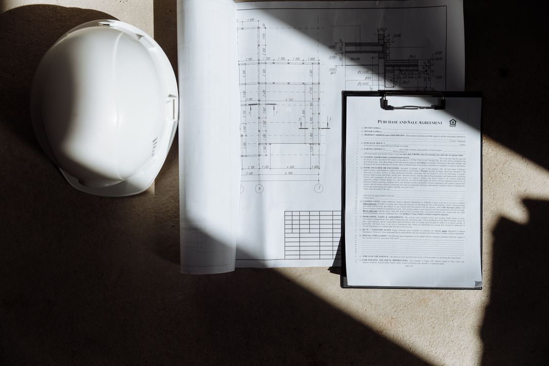 Construction floor plans, contracts and documents spread on a desk in sunlight