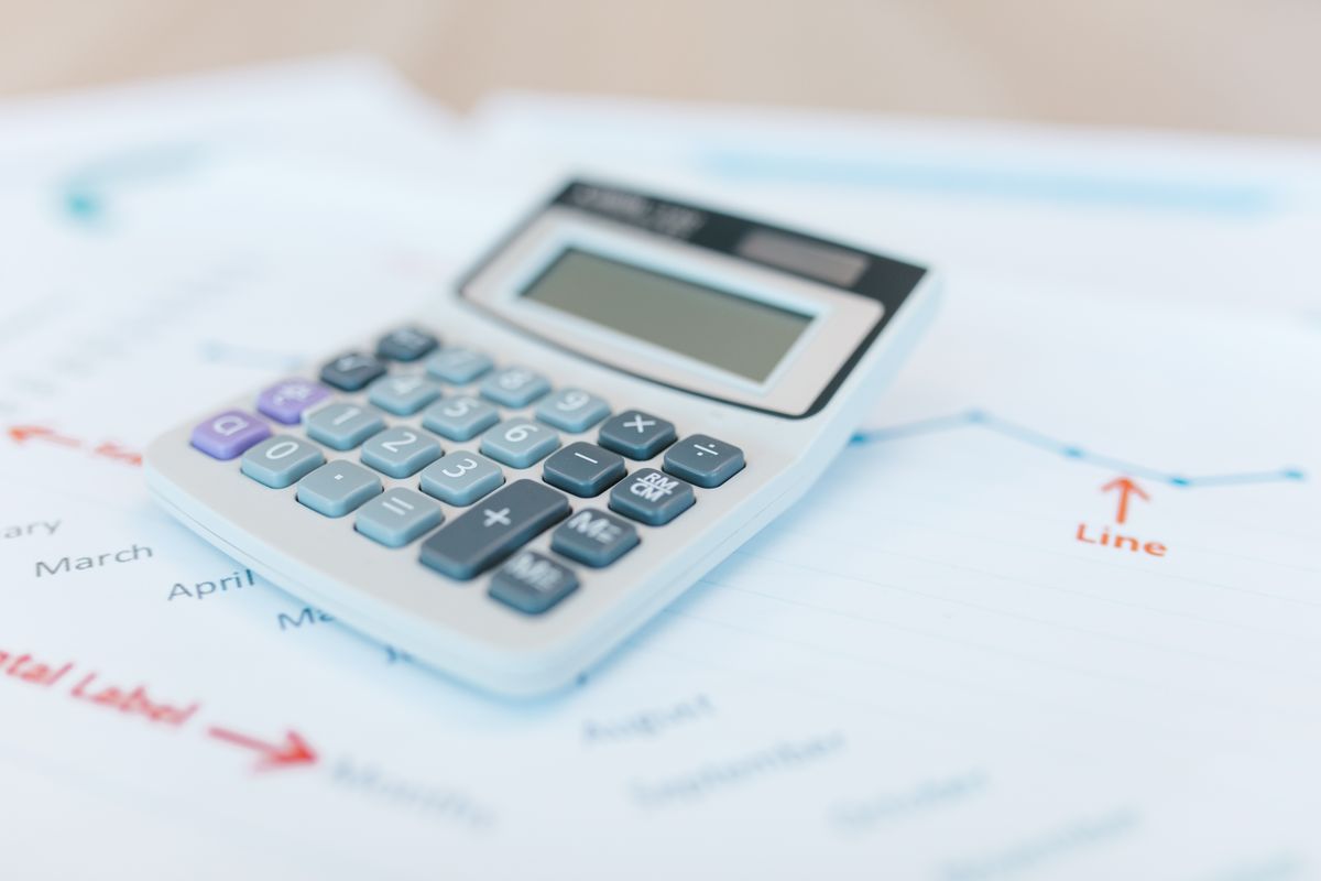 Calculator on top of financial analysis papers with graphs and charts for cash flow review