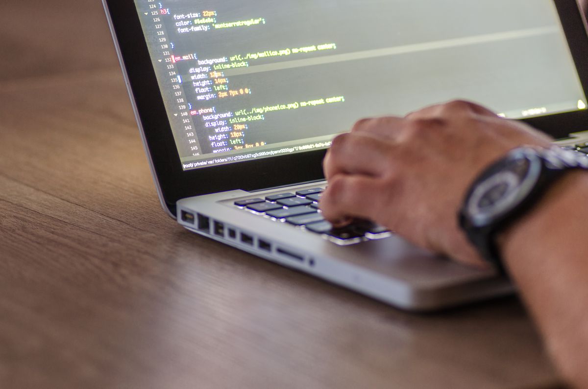 Développeur écrivant du code sur un ordinateur portable dans un espace de travail moderne