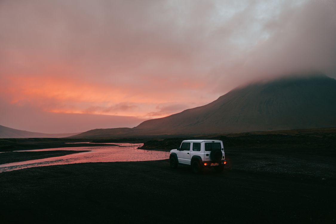 Modified 4x4 facing a scenic Icelandic river with mountains behind
